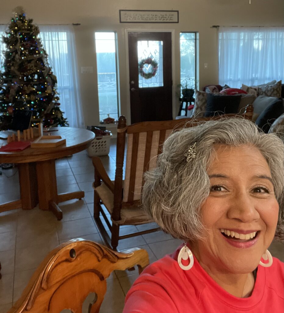 Smiling woman with christmas tree in background. 